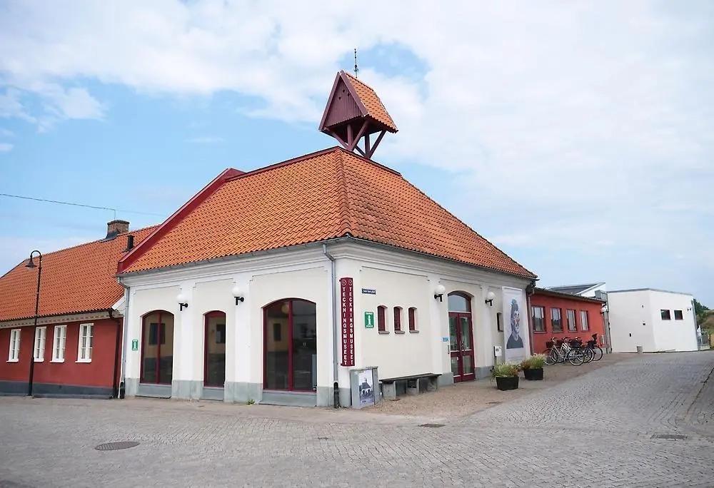 En ljus byggnad med orange tak vid Hästtorget i Laholm.