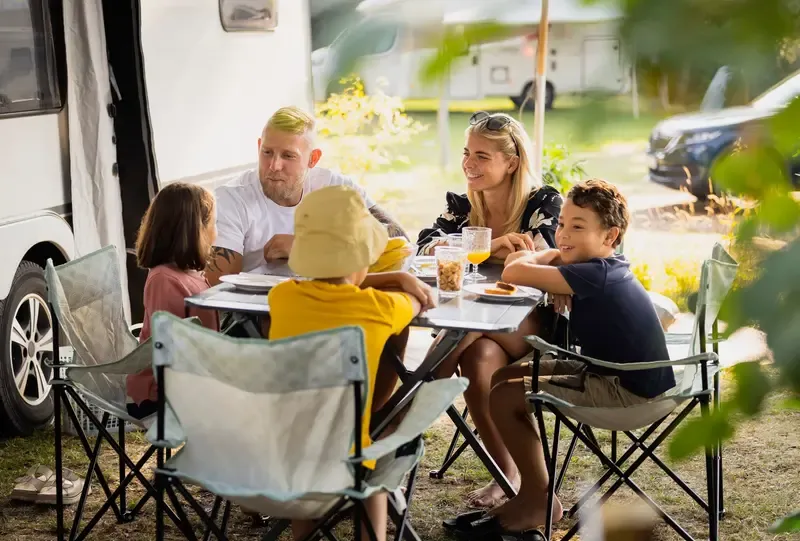 Familj runt ett campingbord